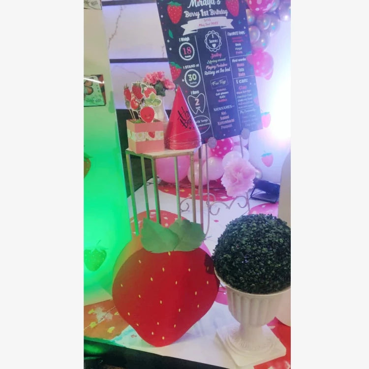 Get Berry First Birthday Decor with strawberry-themed table props and floral decorations